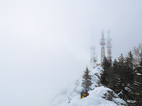 A view of a communication tower in the fog on top of a mountain
