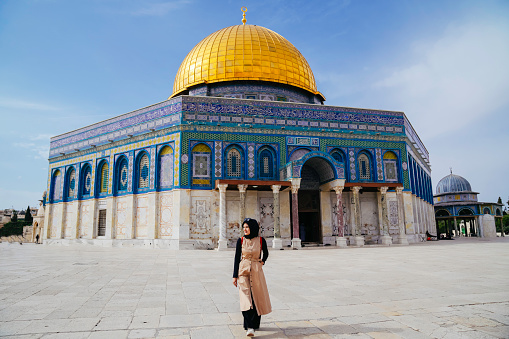 asian muslim woman walking with dome of rock at the background
