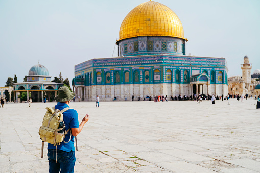 asian man praying with dome of rock at the background