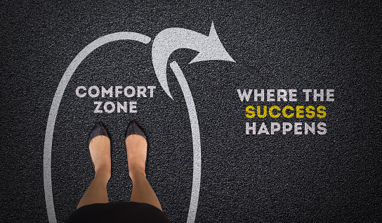 Comfort Zone and Success Concept with businesswoman feet standing on asphalt road with success arrow direction. Top view of Business lady change and decision