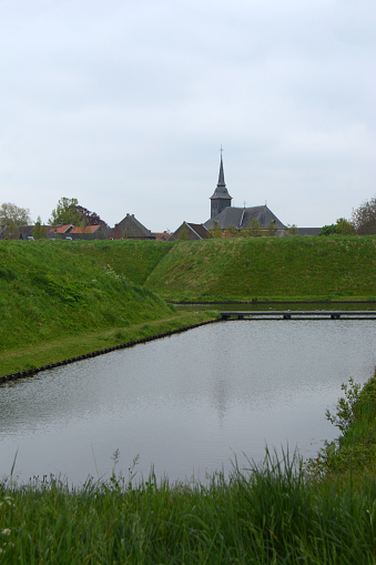 Limburg Stevensweert: Moat and fortified wall. In the background idyllic village view.