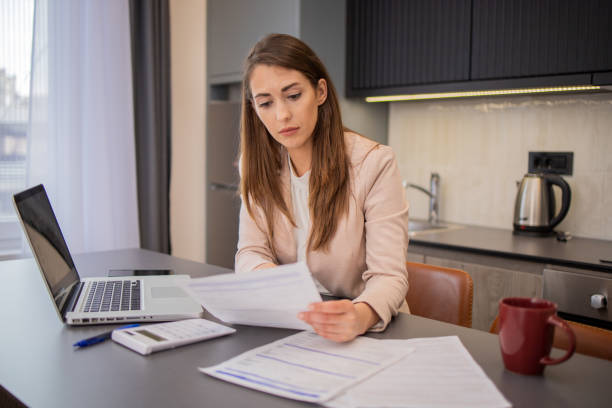 istock Young woman using calculator while going through bills and home finances 1495429634