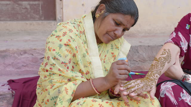Mehendi artist paint henna on female hand, Rajasthan, India