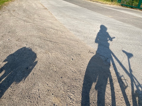 Long shadows while walking the dog with a bike