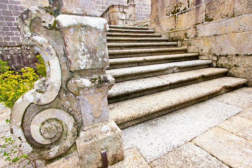 Monumental stone facade staircase and volute carving decoration, ancient baluster of San Clodio monastery church, Leiro, Ourense province, Galicia, Spain. Wide angle view.