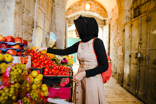 asian muslim woman buying fruit at street market in old city of Jerusalem