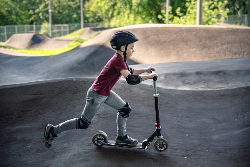 Boy riding push scooter at the outdoors pumptrack