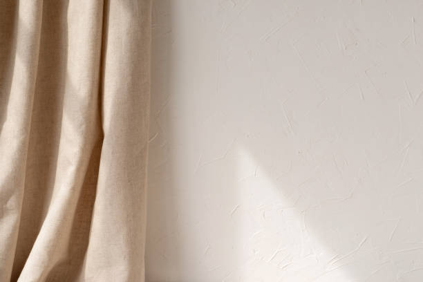 istock Empty white wall with geometric sun light ray pattern, beige linen curtain, warm neutral interior design background 1495446049