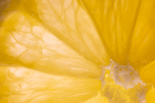 A mesmerizing macro capture of a lemon slice, brilliantly backlit, showcasing its vibrant colors and intricate texture