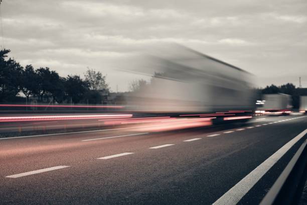 un camion che guida sull'autostrada al crepuscolo. motion blur sull'autostrada. scatto serale di un camion. concetto di trasporto internazionale e logistica. immagine quasi monocromatica. - personal land vehicle foto e immagini stock