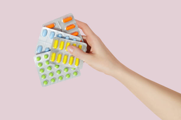 istock Multicolor pills tablets in the woman hand on pink background. Top view. Flat lay. Copy space. Medicine concept 1495448421