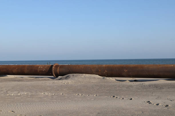 una tubería de acero en la playa para transportar arena - draga fotografías e imágenes de stock