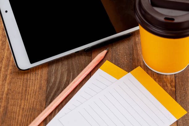 tablet screen,coffee, pen and notepads on wooden floor