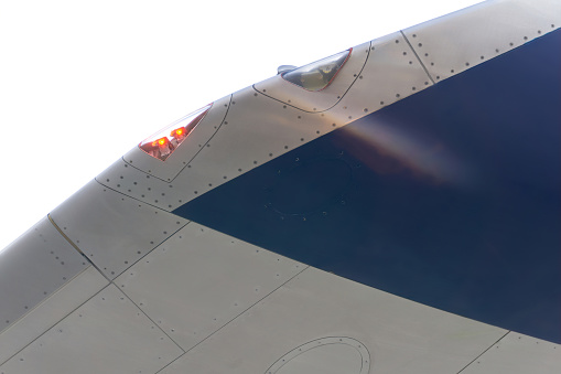 White and blue airplane wing with signal lights close up