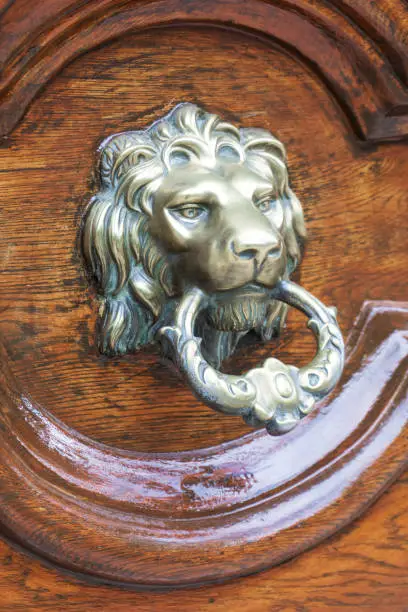 Photo of Antique metal lion head door knocker on a wooden door