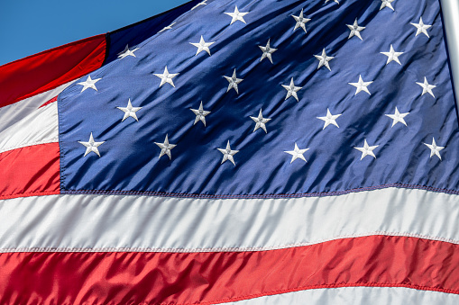 American flag waving on pole with bright vibrant red white and blue colors, negative space