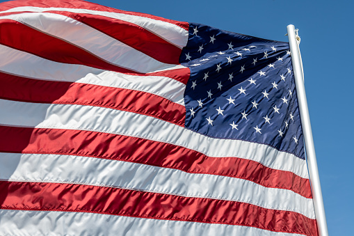 The national flag of the United States of America waving in the wind on a clear day. The flag has become a powerful symbol of Americanism