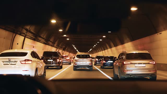 Cars move in the tunnel in the general flow. The camera shoots from the car