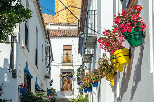Narrow streets in the center of Estepona, typical Andalusian town, with white houses adorned with colorful flower pots located on the Costa del Sol, Malaga province, southern Spain
