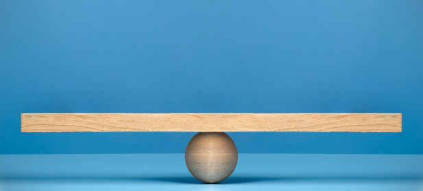 Stability, balance and equality concept. Wooden scale on blue background.