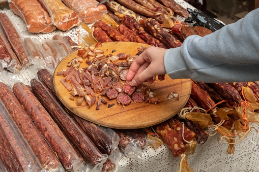 Close up pieces of Charcuterie cured meat on display for tasting on display at a market stall. Tasting of many types of dried meat.