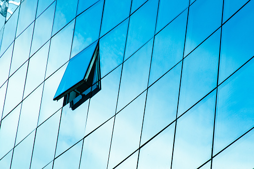 Detail of a glass building with sky reflection in it. Variation with different colour windows.