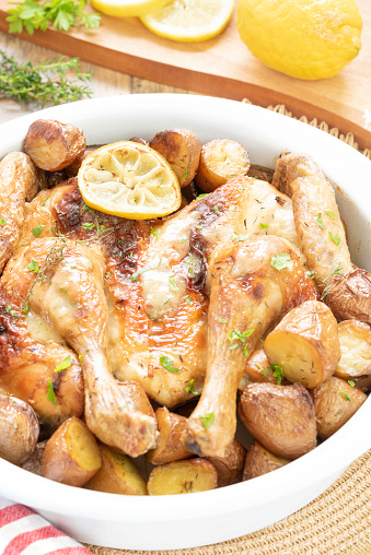 Healthy homemade spatchcocked chicken with caramelized potatoes and citrus gravy, thyme and parsley in a white serving dish