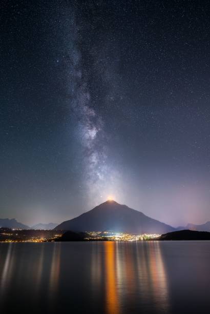 tomada vertical da via láctea sobre o lago thun e o monte niesen luzes sobre o município de spiez - lake thun switzerland night lake - fotografias e filmes do acervo