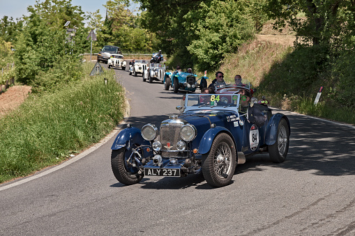 vintage racing car Aston Martin Le Mans (1933) leads a line of classic cars in historical race Mille Miglia. May 17, 2014 in Colle di Val d'Elsa, Tuscany, Italy