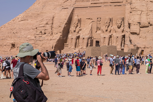 Nubia, Egypt - April 27, 2023: Photographer and long lines of tourists in front of the Temple of Ramses II in Abu Simbel