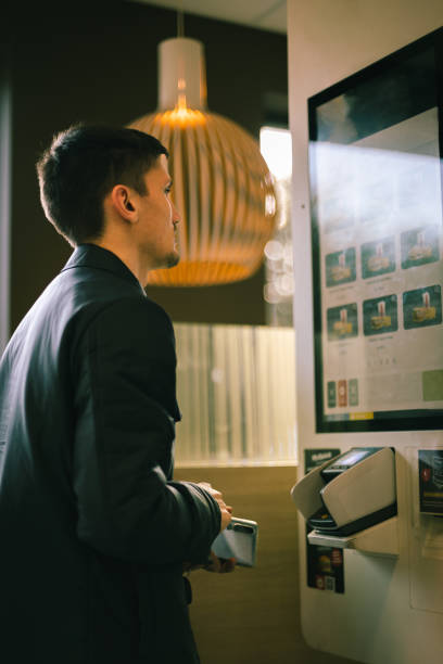 istock A young man makes an order for fast food on a scoreboard screen in a diner. 1495482933