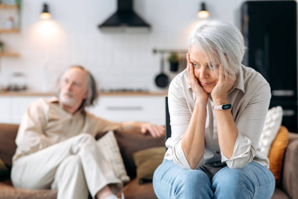 istock Mature caucasian spouses misunderstanding each other, experiencing crisis in relationship, offended wife looks away disappointedly, the husband sits in defocus on background. Quarrel, resentment 1495486148
