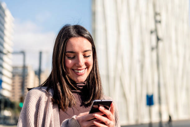 istock woman smiling happy while texting on her phone 1495501914