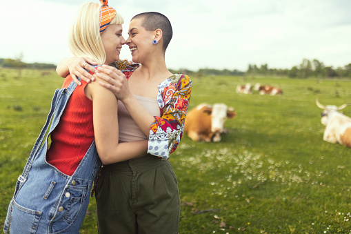 A gay loving couple stands embracing in a pasture and kissing