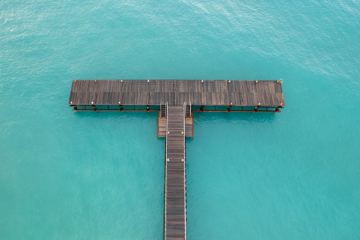 Drone aerial of empty pier in the ocean. Empty dock blue turquoise ocean water.