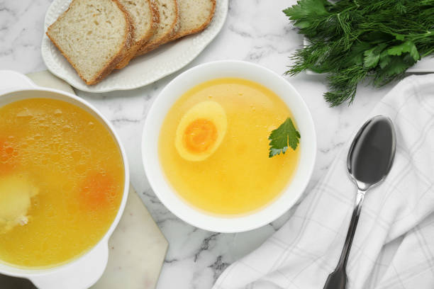 istock Delicious bouillon served on white marble table, flat lay 1495502595