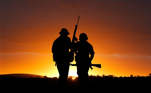 Silhouette of an kneeling Turkish soldier shooting at target at sunset