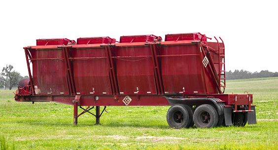 Large red commercial industrial agriculture dry fertilizer transport tender. Holding container used for spreading over large parcels of crops
