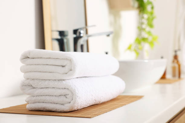 istock Stacked soft towels on white table in bathroom. Space for text 1495505374