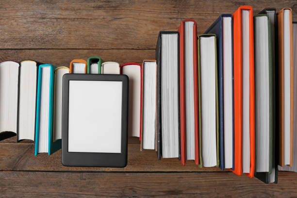 istock Portable e-book reader on hardcover books on wooden table, flat lay 1495506470