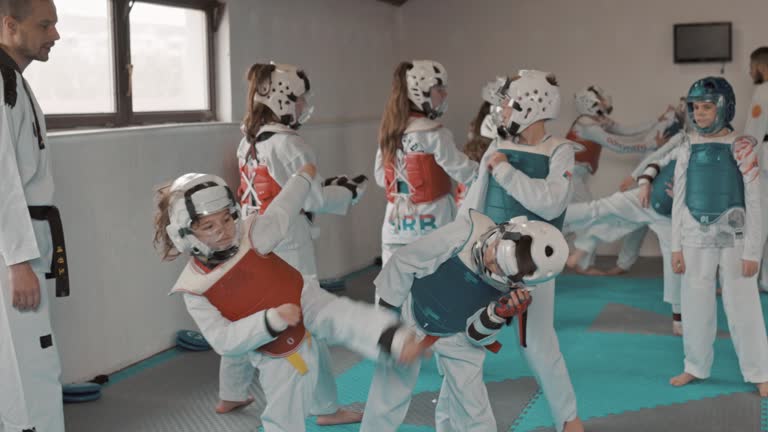 Large group of young taekwondo fighters in uniform train under the guidance of a martial arts coach