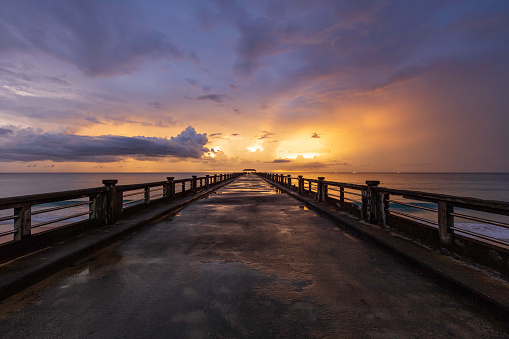 Old bridge pier against beautiful sunset sky after the rain.