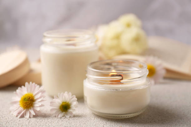 istock Burning scented candles and chamomile flowers on light gray textured table, closeup. Space for text 1495508666