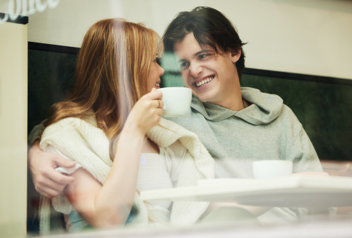 Gen z, student couple and coffee shop window of date together with love and care in cafe. Restaurant, relax and happiness of a teen man and girl with happy smile from teenager relationship in morning