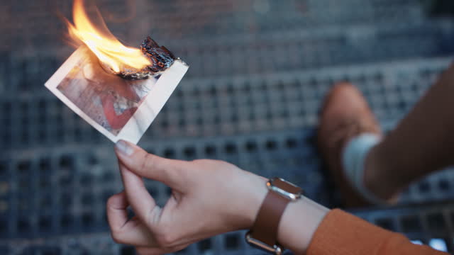 Beautiful sad woman burning photograph of her ex-boyfriend lover
