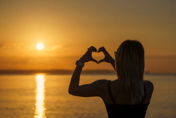 istock Woman's hands making a heart shape over a sunset landscape 1495523002