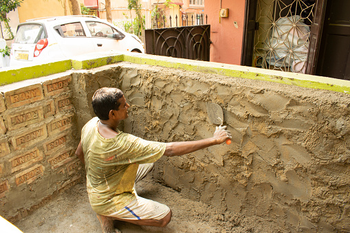 kolkata, west bengal, india - june 1, 2023 : local mason constructing cement plaster on the wall