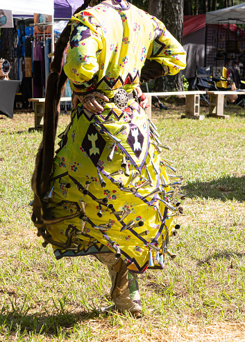 Young jingle dancer, a Native American woman wearing a jingle dress and beaded moccasins in the Gathering of the People Pow Wow in Evans, Georgia.