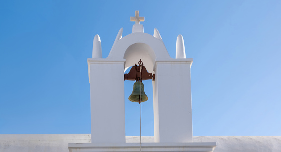 Small orthodox church belfry, white color chapel roof on clear blue sky background, Greece