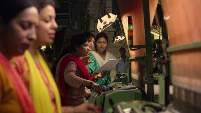 Female workers operating manufacturing equipment at textile factory